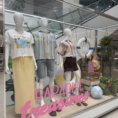 Mannequins in a store window display with 'Paradise Treasures' text.